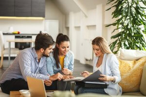 Female real estate or listing agent helping young couple buy or sell a house