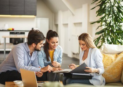 Female real estate or listing agent helping young couple buy or sell a house