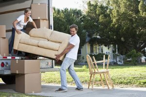 Young couple moving to a new house and packing a move-in truck