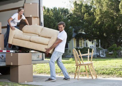 Young couple moving to a new house and packing a move-in truck
