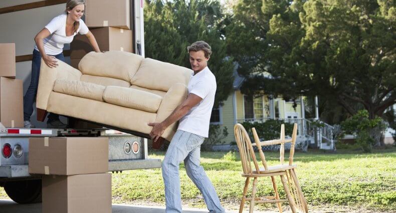 Young couple moving to a new house and packing a move-in truck