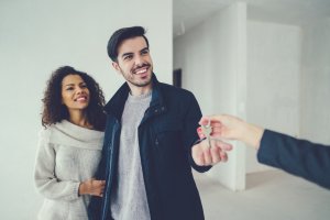 A couple getting the keys from their real estate agent for their new home