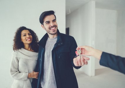 A couple getting the keys from their real estate agent for their new home