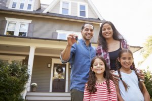 Happy family outside of their newly-bought home, considering home buying guide.