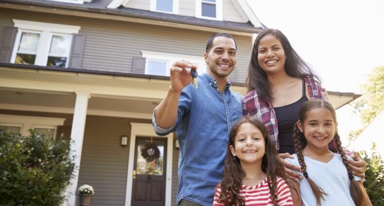 Happy family outside of their newly-bought home, considering home buying guide.