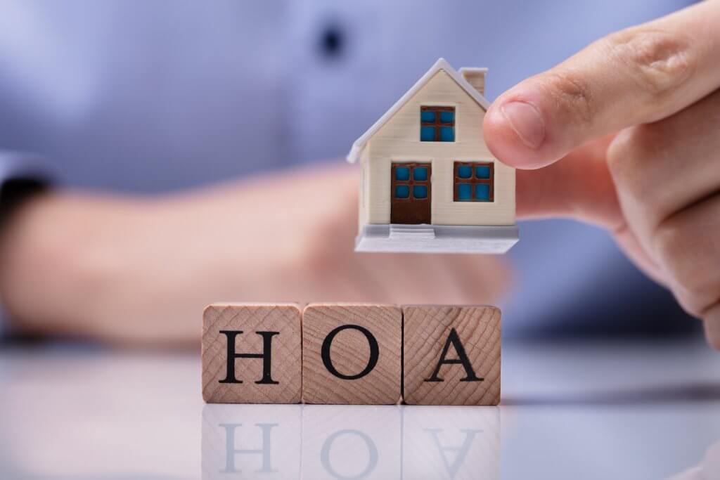 Businessman Placing House Models On HOA Cubic Blocks