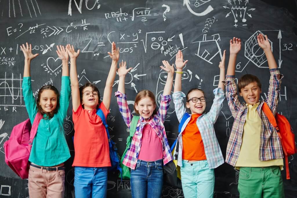 real estate agent helping you to find a high-rated school concept; Group of happy schoolchildren standing in front of the blackboard with hands up