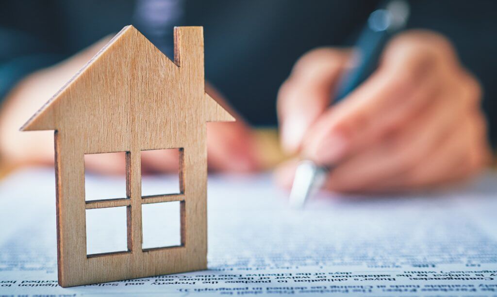 buy a new home concept; man signing a contract to purchase a new house