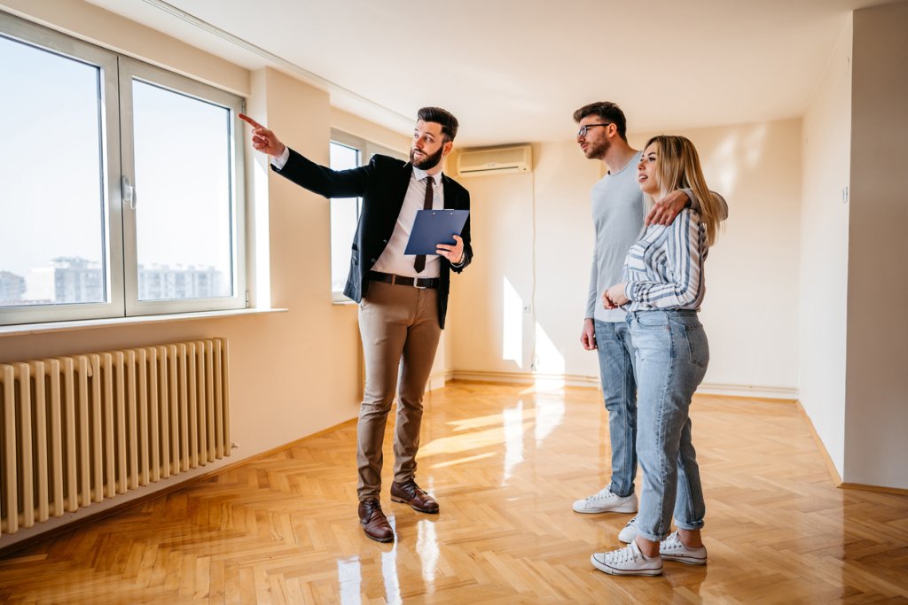 A male real estate agent showing an apartment for sale to a young couple