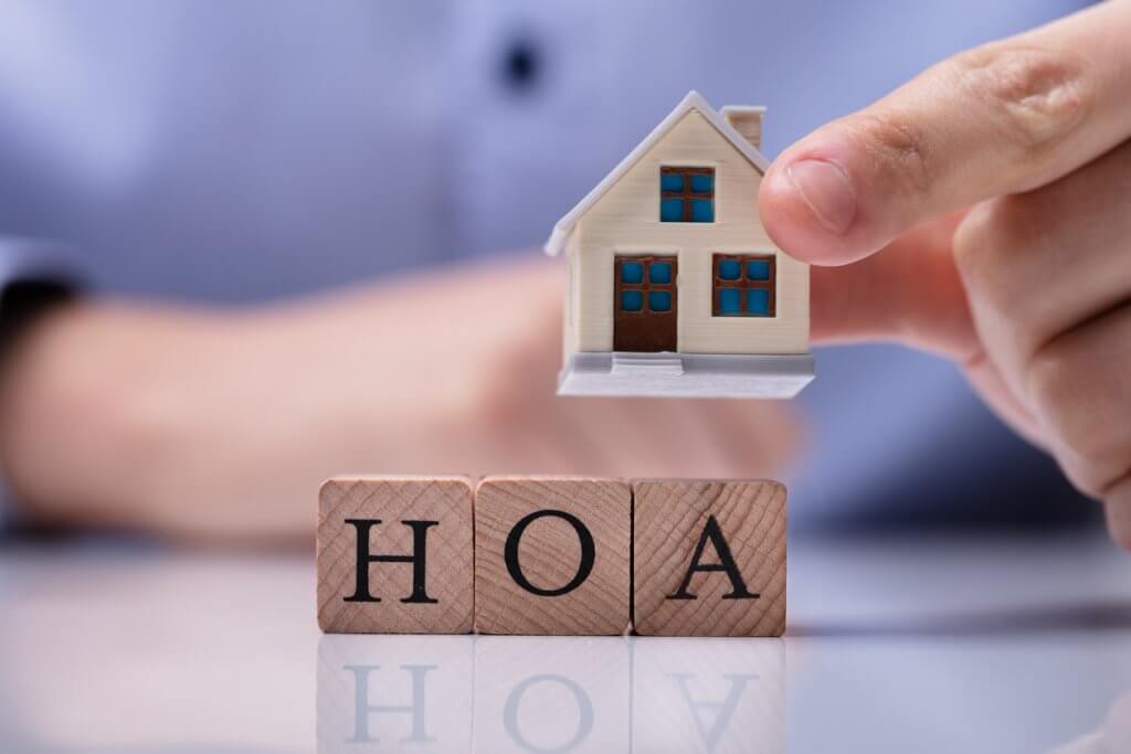 HOA dues concept; Businessman Placing House Models On HOA Cubic Blocks