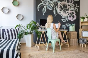 Woman sitting on her working area with chalkboard wall as DIY home decor