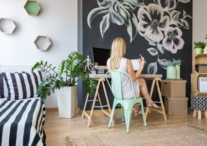 Woman sitting on her working area with chalkboard wall as DIY home decor