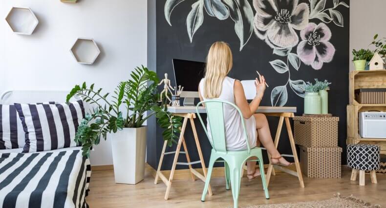 Woman sitting on her working area with chalkboard wall as DIY home decor